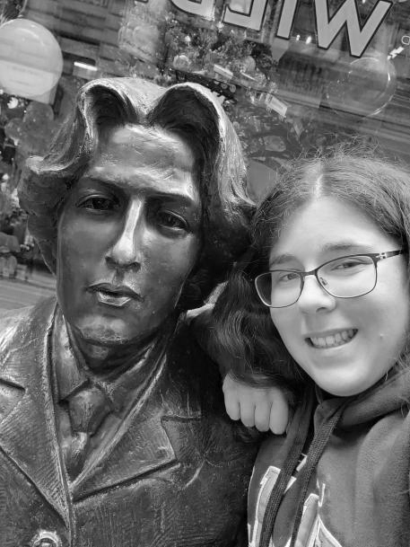 Bri leaning against the shoulder of a statue of Oscar Wilde.
